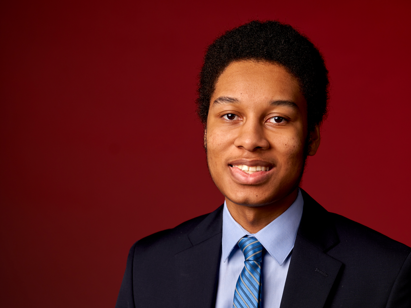 Photo of Matthew Turk in front of a red background.